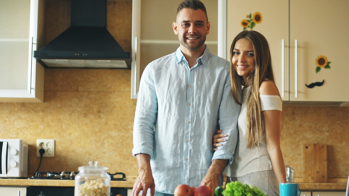 Portrait of loving couple cooking breakfast smiling ang looking into camera in the kitchen at home